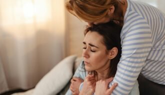 Two women sharing an emotional moment through a comforting hug indoors.