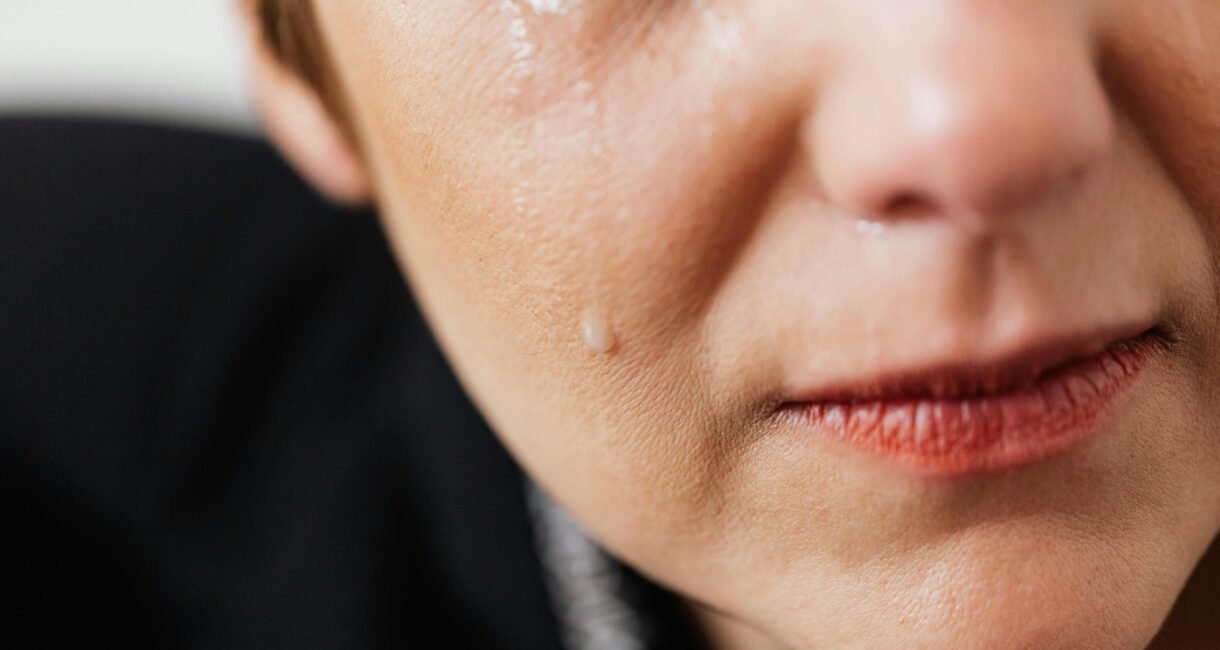 Closeup of crop anonymous sad adult female with makeup crying because of emotional problems