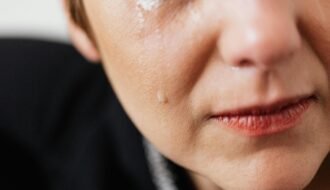 Closeup of crop anonymous sad adult female with makeup crying because of emotional problems