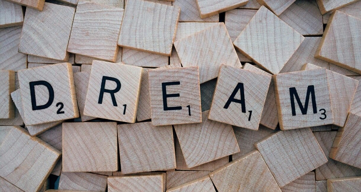Close-up of wooden Scrabble tiles spelling the word 'DREAM', symbolizing creativity and imagination.