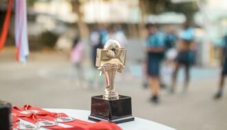 Close-up of a polished soccer trophy with medals at an outdoor sports award ceremony.