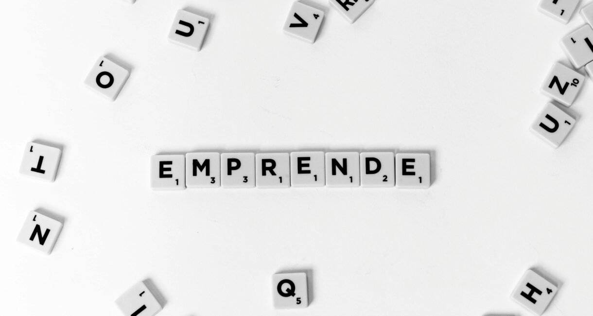 Scrabble tiles laid out to spell 'EMPRENDE' creatively on white background.