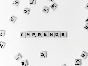 Scrabble tiles laid out to spell 'EMPRENDE' creatively on white background.