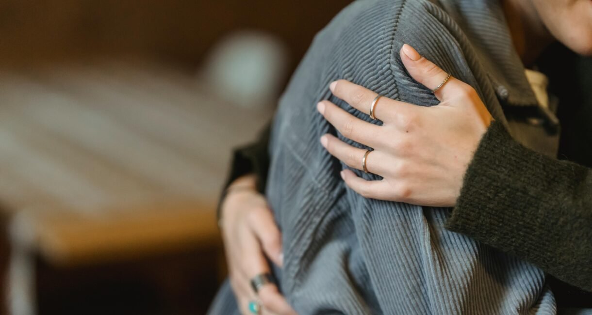 High angle of crop anonymous delicate female cuddling crying girlfriend suffering from misfortune and grief