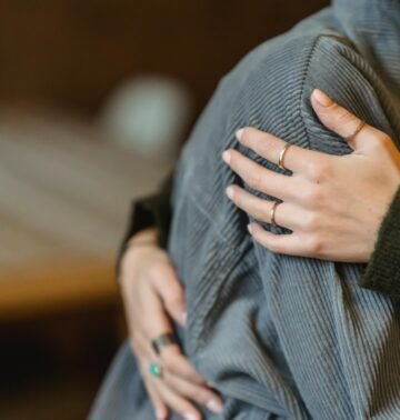 High angle of crop anonymous delicate female cuddling crying girlfriend suffering from misfortune and grief