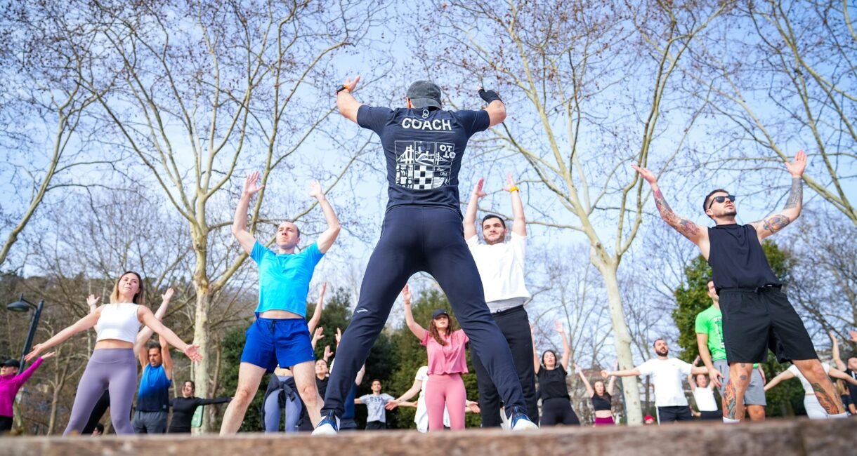 Group exercise session in a sunny Istanbul park led by a fitness coach outdoors.